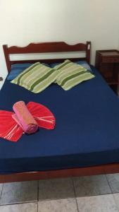 Una cama azul con dos almohadas encima. en Casa próximo a praia com churrasqueira e ar condicionado! en Caraguatatuba