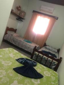 - une chambre avec 2 lits et une fenêtre dans l'établissement Casa próximo a praia com churrasqueira e ar condicionado!, à Caraguatatuba
