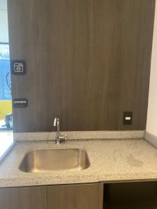 eine Küchentheke mit einem Waschbecken und einem Spiegel in der Unterkunft La Boutique station Brooklin in São Paulo