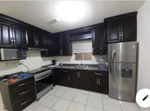 a kitchen with black cabinets and a stainless steel refrigerator at Casa con alberca compartida Netflix Disney + Amazon TV in Hermosillo