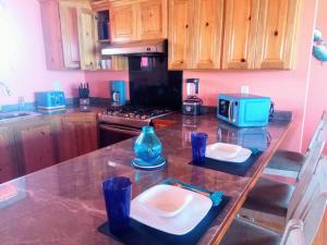 a kitchen with a counter with a table with plates and a microwave at Casa Corazon Striking Beach Home in Utila