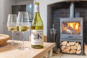 uma garrafa de vinho e dois copos de vinho numa mesa em Beautiful 2 Bedroom Cottage in Oxton em Oxton