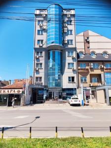 un bâtiment dans une rue avec une voiture garée devant dans l'établissement Hotel Rile Men Blue, à Niš