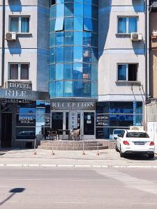 um carro branco estacionado em frente a um edifício em Hotel Rile Men Blue em Niš