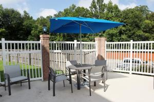 a table and chairs with a blue umbrella on a patio at Holiday Inn Express Baton Rouge North, an IHG Hotel in Zachary