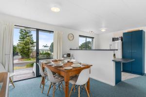 a kitchen and dining room with a wooden table and chairs at The Summer Pad - Omaha Holiday Home in Warkworth