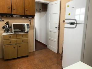 a kitchen with a white refrigerator and a microwave at Quarto em apartamento in São Paulo