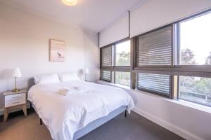 um quarto branco com uma cama e janelas em Olympic Park 2 Bedrooms Charm Family Friend Free Parking em Sydney