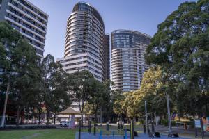 zwei hohe Gebäude in einem Park mit Bäumen in der Unterkunft Olympic Park 2 Bedrooms Charm Family Friend Free Parking in Sydney