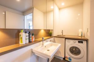 ein Badezimmer mit einem Waschbecken und einer Waschmaschine in der Unterkunft Olympic Park 2 Bedrooms Charm Family Friend Free Parking in Sydney