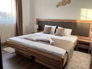 1 dormitorio con 1 cama grande y cabecero de madera en SKY LUX apartman, en Surčin