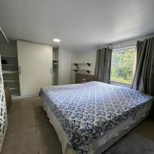 una camera da letto con un letto con un piumone blu e una finestra di STUDIO 201 | WIFI 600MB | RESIDENCIAL JC, um lugar para ficar. a Belém Novo