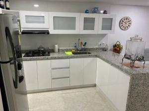 a kitchen with white cabinets and a clock on the wall at Perla Santa - Luxury Condo in Santa Marta
