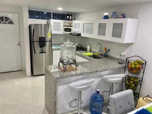 a kitchen with a counter with bar stools and a refrigerator at Perla Santa - Luxury Condo in Santa Marta