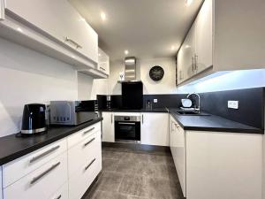 エペルネーにあるLe Domaineの白いキャビネットと黒いカウンタートップを備えたキッチン +7枚の写真