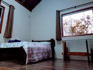 a bedroom with a bed and a large window at Chalé toca do lobo in Sao Jorge