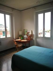 a bedroom with a bed and a desk and windows at Blue Room Shared House Terrace above in Genoa