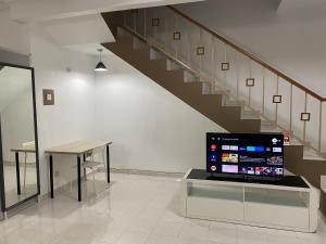 a room with a staircase and a table and a television at Comfy Sutera Seberang Jaya in Kampong Belah Dua
