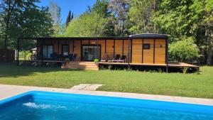 una casita con una piscina frente a ella en Naturaleza y Comodidad: Cabaña en Barrio Cerrado en 