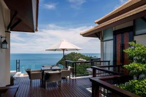 a balcony with a table and an umbrella at Banyan Tree Samui in Lamai
