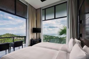 a bedroom with a bed and a large window at Banyan Tree Samui in Lamai