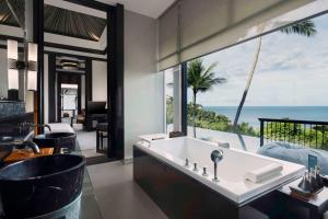 a bathroom with a tub and a view of the ocean at Banyan Tree Samui in Lamai