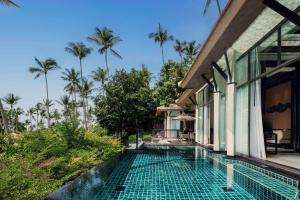 an infinity pool in front of a house with palm trees at Banyan Tree Samui in Lamai