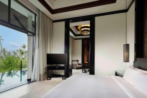 a bedroom with a large bed and a tv at Banyan Tree Samui in Lamai
