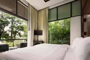 a bedroom with a large bed and a large window at Banyan Tree Samui in Lamai