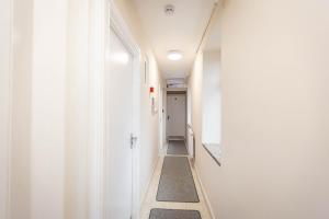 a hallway with white walls and a long hallway at Airstaybnb in Manchester