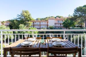 una mesa de madera con copas de vino en el balcón en Privilegiado-Tarragona-50mPlaya-WIFI-Pool-Relax8, en Tarragona
