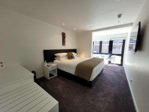 a bedroom with a large bed and a window at The Devon Hotel A Heritage Hotel in New Plymouth