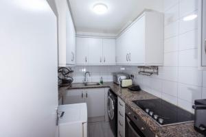una cocina con armarios blancos y fregadero en Airstaybnb en Mánchester