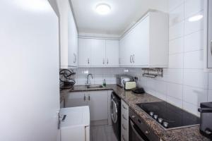 een keuken met witte kasten en een spoelbak bij Airstaybnb in Manchester +48 foto's
