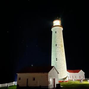 a lighthouse is lit up at night at Motel du Haut Phare in Cap-des-Rosiers