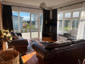 uma sala de estar com sofás de couro e uma televisão em Pinot Villas em Martinborough