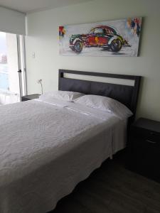 1 dormitorio con 1 cama y una pintura de un coche de carreras en Depto. Nautilus Piso 11, en Iquique