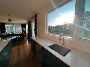 a kitchen with a sink and a large window at Pinot Villas in Martinborough +110 photos