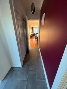 an empty hallway with a red wall and a door at Pinot Villas in Martinborough 