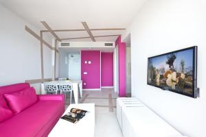 a living room with a pink couch and a tv at Ryans Ibiza Apartments - Only Adults in Ibiza Town