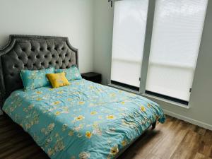 a bedroom with a bed with a blue comforter and two windows at Feel Home at Frisco in Frisco