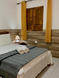 1 dormitorio con 1 cama con cortinas amarillas y espejo en Pousada Sitio Araça, en São Miguel dos Milagres