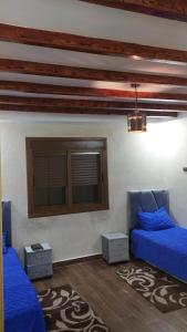sala de estar con 2 camas y ventana en Chez karim, en Ifrane