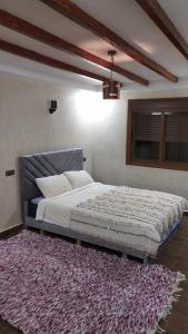 a bedroom with a large bed with a rug at Chez karim in Ifrane
