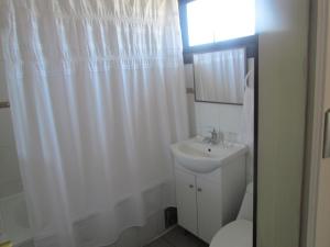 a bathroom with a white shower curtain and a sink at Hostería Antupirén in Hornopiren
