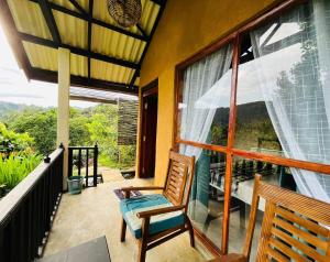 een balkon met 2 stoelen en een groot raam bij Rainforest Nature House in Deniyaya