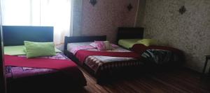 Habitación con 2 camas y almohadas coloridas. en La Perla Cuencana Hostal en Cuenca
