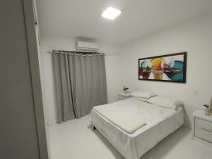a white bedroom with a bed and a window at Ampla, 180 graus de vista mar. in Ilhéus