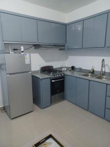 een keuken met blauwe kasten, een fornuis en een koelkast bij Plataview Apartahotel apt 3C in Monte Plata