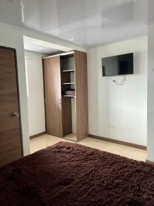 1 dormitorio con 1 cama y TV de pantalla plana en Amarena Hotel Boutique, en Manizales